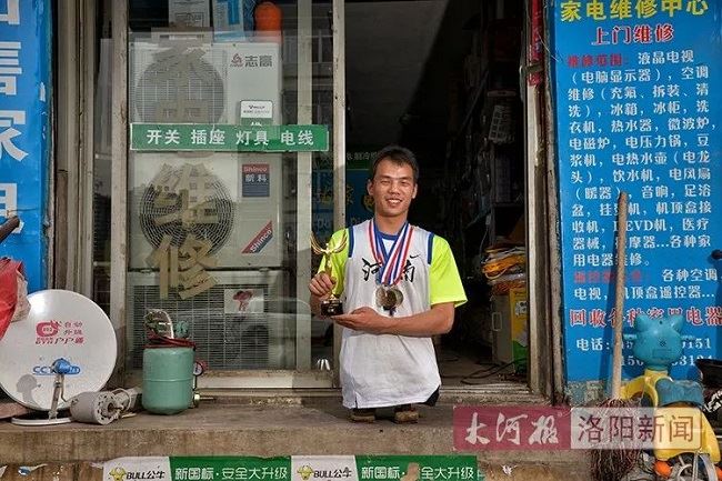 图为杜亚甫展示他获得的多个体育项目奖杯和奖牌