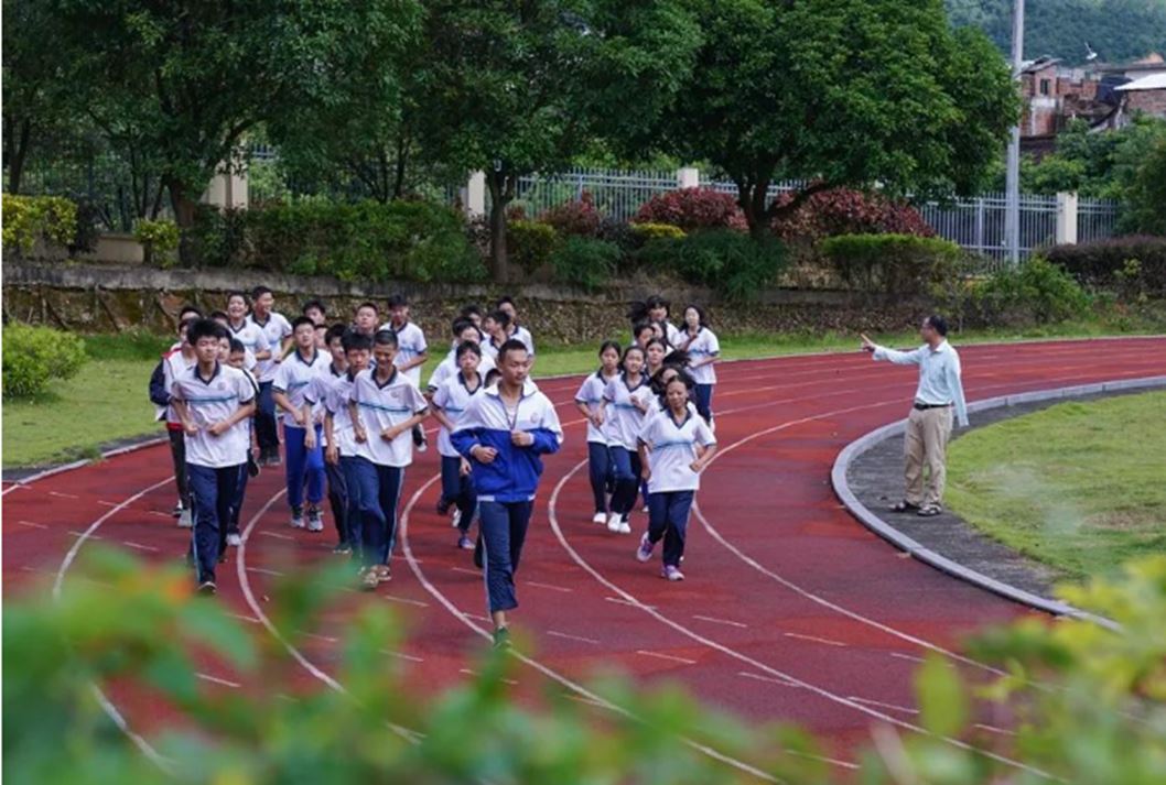 图为课间操期间梁木山督促学生跑步锻炼